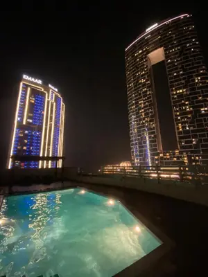 a swimming pool on the roof of a building at night at Wonderful two bed room with full marina view in Dubai