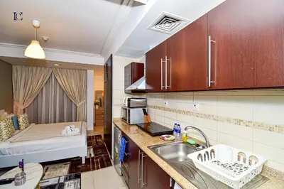 a kitchen with a sink and a bed in a room at Luxury Escapes - Cozy Studio with Balcony near Metro - Goldcrest 2 JLT in Dubai