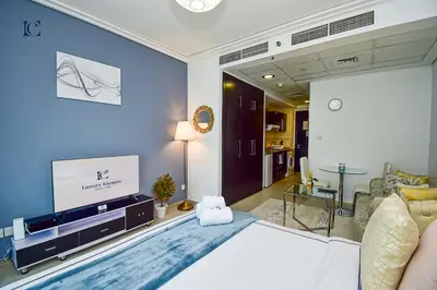 a bedroom with a large bed and a living room at Brand New Studio Apt - Near JLT Metro in Dubai