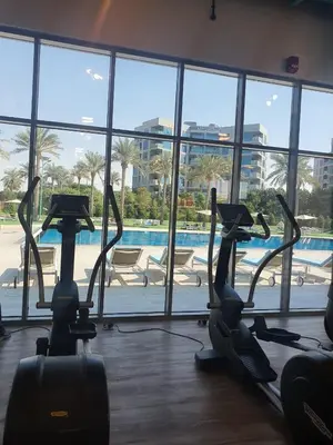 a gym with cardio machines in a building with a pool at Cozy 1-bedroom apartment in Dubai South with Pool in Dubai