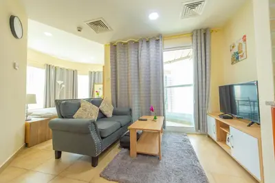 a living room with a couch and a television at Luxury Escapes - Modern Budget studio with balcony in JLT! in Dubai