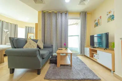 a living room with a couch and a tv at Luxury Escapes - Modern Budget studio with balcony in JLT! in Dubai