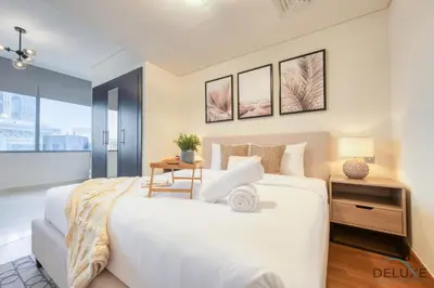 a bedroom with a large white bed and a window at Calm Studio at Sky Gardens DIFC by Deluxe Holiday Homes in Dubai