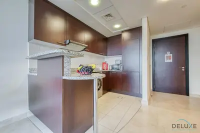 a kitchen with wooden cabinets and a counter top at Oceanic Studio at Sky Gardens DIFC by Deluxe Holiday Homes in Dubai