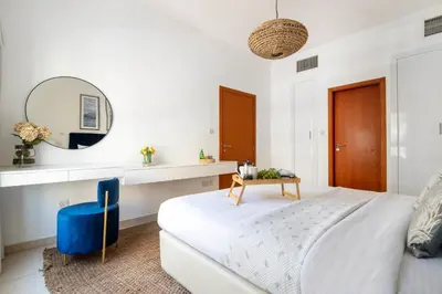 a white bedroom with a large bed and a mirror at Frank Porter - Al Thayyal 2, The Greens in Dubai