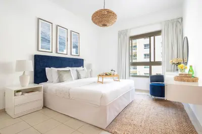 a white bedroom with a large bed and a desk at Frank Porter - Al Thayyal 2, The Greens in Dubai