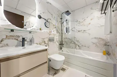 a white bathroom with a sink and a toilet and a tub at Great Gatsby's Home in Dubai
