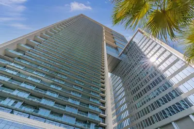 a tall building with a palm tree in front of it at Silkhaus comfy furnished studio in the heart of DIFC in Dubai