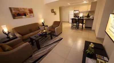 a living room with couches and a table and a kitchen at Ivory Grand Hotel Apartments in Dubai