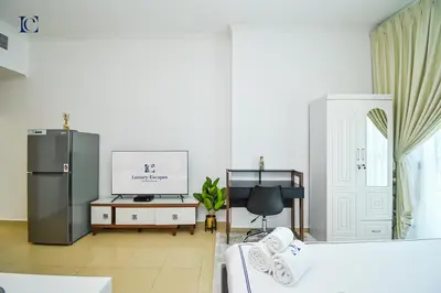 a living room with a refrigerator and a tv at Luxury Escapes - Modern Studio near Metro in X1 Tower JLT in Dubai