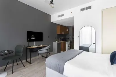 a bedroom with a bed and a desk and a kitchen at Silkhaus Dubai Financial Center studio in Burj Daman in Dubai