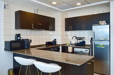 a kitchen with a counter with a refrigerator and stools at Luxury Escapes - Marina Views 1BR Apartments - Bay Central Dubai Marina in Dubai