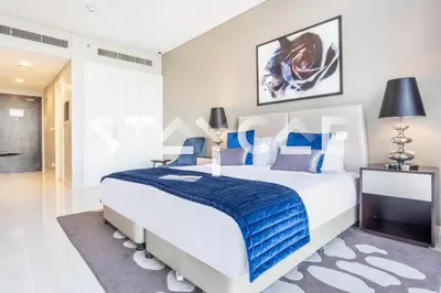 a bedroom with a large bed with a blue blanket at Staycae Holiday Homes - Artesia in Dubai