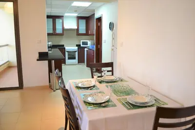 a dining room with a table and chairs and a kitchen at Luxury Escapes - Large 1Bed with balcony and a great marina view in JBR in Dubai