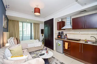 a kitchen and a living room with a couch and a table at Luxury Escapes - Modern Studio Apt - Metro, Beach & Mall mins away in Dubai