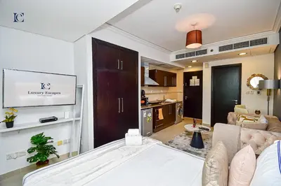 a living room with a bed and a kitchen at Luxury Escapes - Modern Studio Apt - Metro, Beach & Mall mins away in Dubai