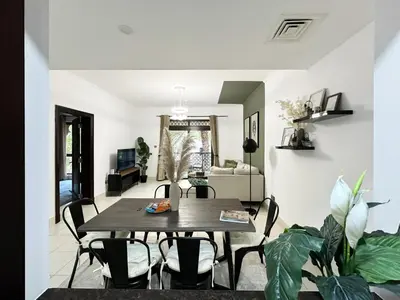 a living room with a wooden table and chairs at Trophy 2BR Aladdin Estate w Burj Khalifa View in Dubai