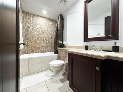 a bathroom with a toilet and a sink and a mirror at Trophy 2BR Aladdin Estate w Burj Khalifa View in Dubai