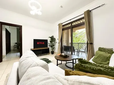 a living room with a white couch and a tv at Trophy 2BR Aladdin Estate w Burj Khalifa View in Dubai
