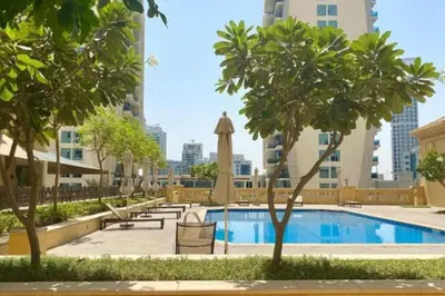 a pool with chairs and trees and buildings at Regent Sea View 2BR Apartment JBR Beach Walk - next to Bluewater Island & Dubai Eye in Dubai