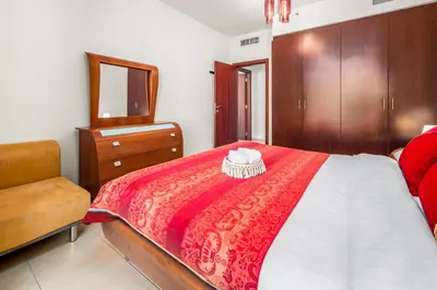 a bedroom with a bed with a mirror and a chair at Lovely 2-bed condo in JBR - 5 mins from beach - Palm View! in Dubai