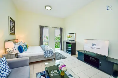 a living room with a bed and a tv at Luxury Escapes - Cozy budget studio near Metro & Ibn Battuta Mall - MOG190 DG in Dubai
