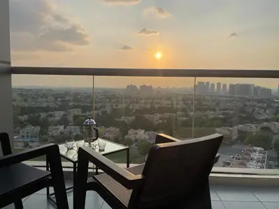 a table and chairs on a balcony with a view of a city at Big studio, Dubai SportCity, parking included in Dubai