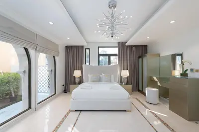 a bedroom with a white bed and a chandelier at Palm Jumeirah - Property Advisers in Dubai