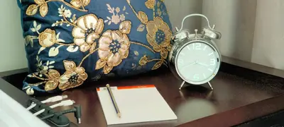 a clock sitting on a table with a pen and a notebook at 2 BR apartment with a beautiful view of the Marina minimum 5 night in Dubai