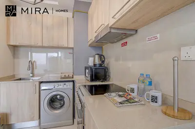 a kitchen with a sink and a washing machine at Mira Holiday Homes - Lovely Studio in AG tower with free parking in Dubai