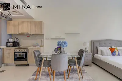 a living room with a kitchen and a table with chairs at Mira Holiday Homes - Lovely Studio in AG tower with free parking in Dubai