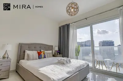 a bedroom with a bed and a large window at Mira Holiday Homes - Lovely Studio in AG tower with free parking in Dubai