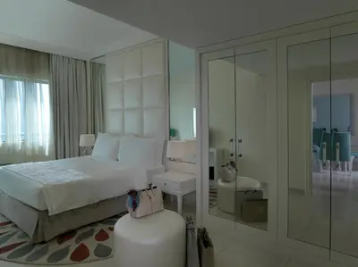 a white bedroom with a bed and a stool at DAMAC Maison Mall Street in Dubai