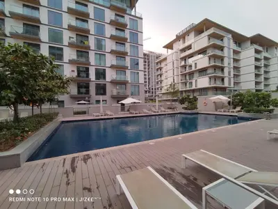 a swimming pool in front of some apartment buildings at Notable 2BR at Sobha Hartland Greens MBR City by Deluxe Holiday Homes in Dubai