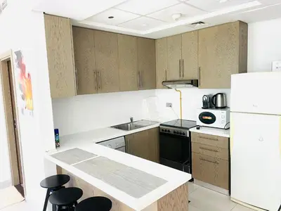a kitchen with wooden cabinets and a white refrigerator at Deluxe One Bedroom Apartment for rent in Dubai Al Barsha south in Dubai