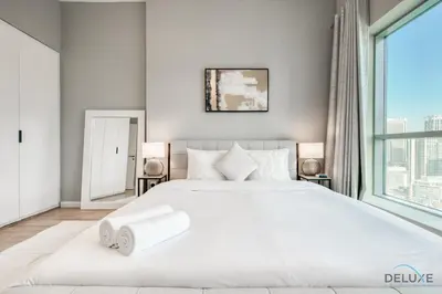 a white bedroom with a large bed and a large window at Elegant 2BR at The Point Dubai Marina by Deluxe Holiday Homes in Dubai