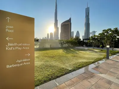 a sign in a park with a view of a city at GuestReady - The Ivory Coast Downtown Views in Dubai