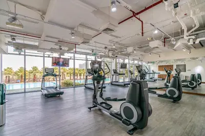 a gym with treadmills and elliptical machines at Silkhaus elegant studio in the central DIFC with balcony and city views in Dubai