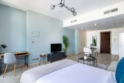 a bedroom with a bed and a desk and a tv at Silkhaus elegant studio in the central DIFC with balcony and city views in Dubai
