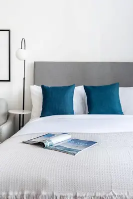 a bed with blue pillows and a magazine on it at Silkhaus elegant studio in the central DIFC with balcony and city views in Dubai