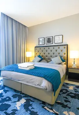 a bedroom with a large bed with a blue rug at Luxury Escapes - Quiet Studio near Expo City and DWC Airport - CELESTIA TOWER in Dubai