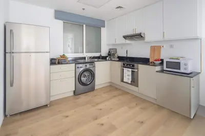 a kitchen with white cabinets and a refrigerator at Frank Porter - Princess Tower in Dubai