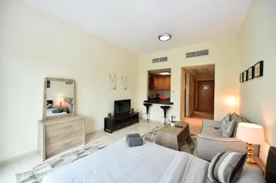 a living room with a bed and a mirror at Luxury Escapes - Stylish Studio Vacation Home near Metro - MOG189 DG in Dubai