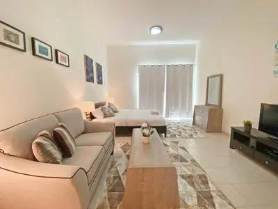 a living room with a couch and a tv at Luxury Escapes - Stylish Studio Vacation Home near Metro - MOG189 DG in Dubai