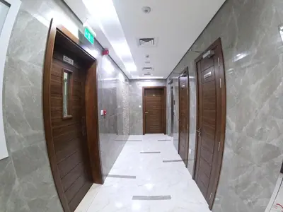 a corridor in a building with wooden doors and a tile floor at Karama Star Residence (Home Stay) in Dubai