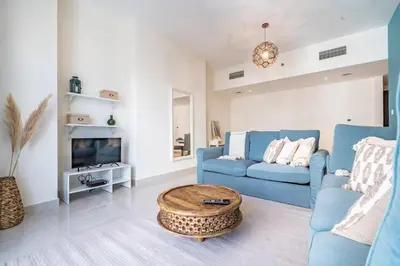 a living room with a blue couch and a coffee table at Stylish Waterfront Apartment With Views on Canal in Dubai