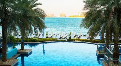 a swimming pool with palm trees and a large body of water at Luxury Apartment Palm Jumeirah in Dubai