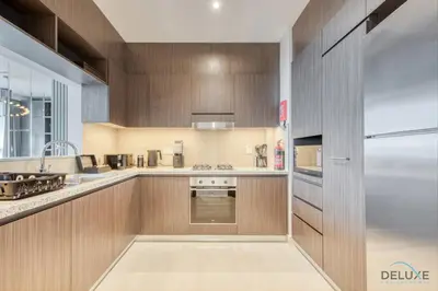 a kitchen with wooden cabinets and a stainless steel refrigerator at Elegant 2BR at Downtown Views Downtown Dubai by Deluxe Holiday Homes in Dubai