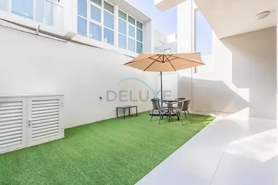 a patio with a table and chairs and an umbrella at Furnished 3-Bedroom Townhouse, Just Minutes Drive from Al Marmoom Heritage Village and Popular Dubai Attractions, Albizia, Damac Hills 2 by Deluxe Holiday Homes in Dubai