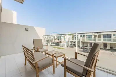 a balcony with chairs and a table and a large window at Furnished 3-Bedroom Townhouse, Just Minutes Drive from Al Marmoom Heritage Village and Popular Dubai Attractions, Albizia, Damac Hills 2 by Deluxe Holiday Homes in Dubai